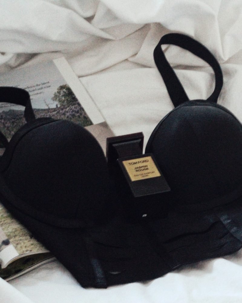 black bra with perfume bottle on bed for blog on female orgasm