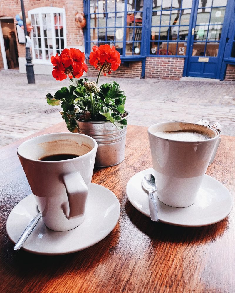 Image of two coffee cups at outdoor cafe for blog on how much to tell your partner about your friends