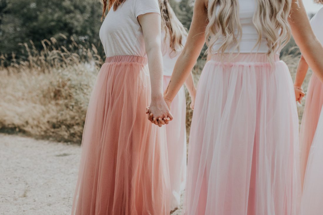 Girls holding hands outside wearing pink skirts - blog on relationship advice from friends