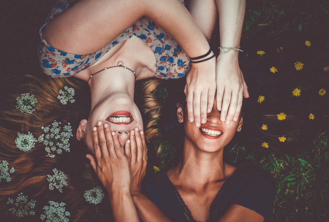 Image of two women lying down in flowers for blog on trusting yourself when dating